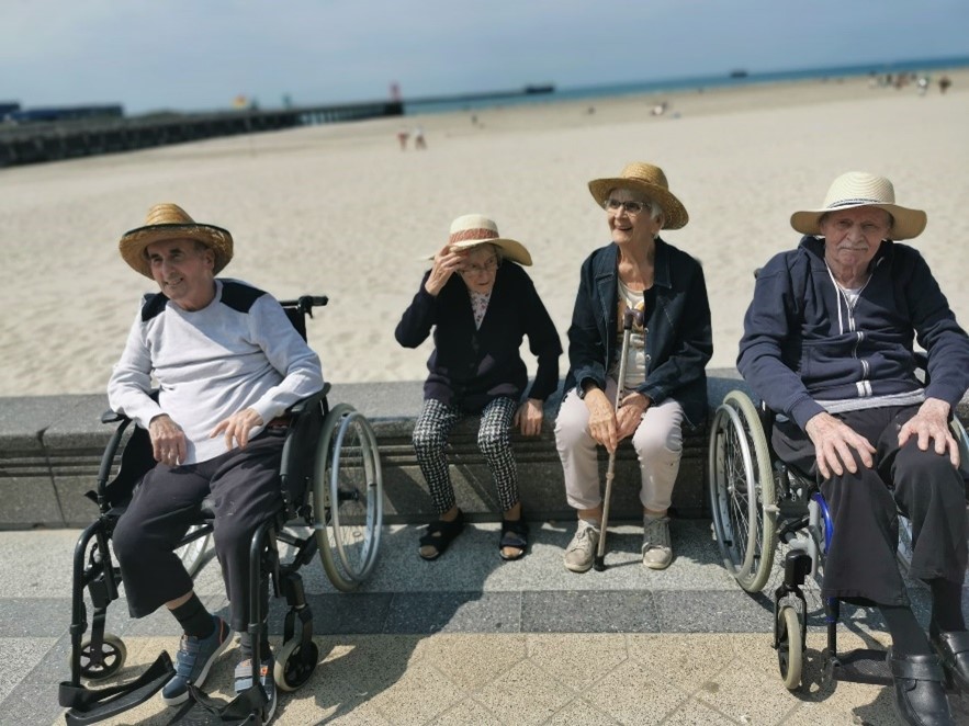 personnes en fauteuil roulant devant la plage