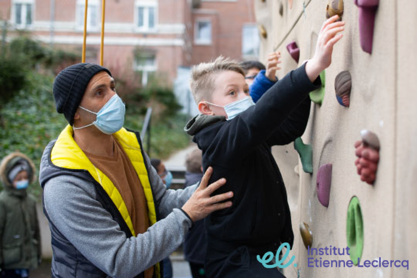 homme aidant un enfant sur un mur escalade